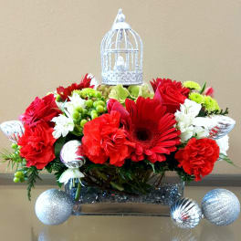 Red flowers arranged with silver ornaments and a decorative birdcage topper