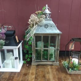 Decorative lanterns with candles and floral accents on a wooden floor