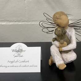 Decorative angel figurine holding a small dog with a Willow Tree card beside it