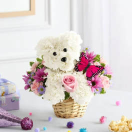 White teddy bear made of flowers in a wicker basket with pink and purple blooms