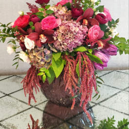 Large bouquet of pink and burgundy flowers in a dark vase