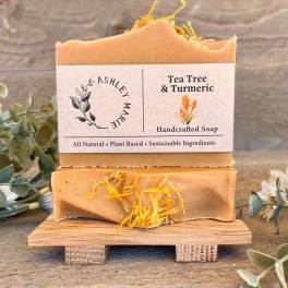 Two bars of tea tree and turmeric soap on a small wooden stand