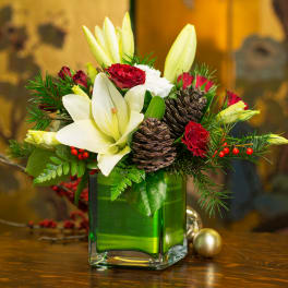 Holiday bouquet of white lilies and red roses in a green glass vase