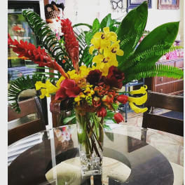 Tropical flower arrangement in a clear glass vase with red and yellow blooms