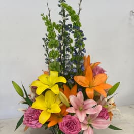 Colorful mixed bouquet with lilies and roses in a low vase
