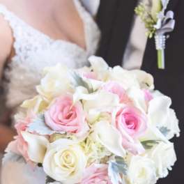Bride holding a pink and white rose bouquet with a matching boutonniere