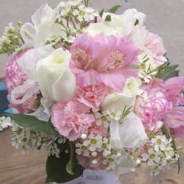 Pink and white bouquet in a clear glass vase with ribbon
