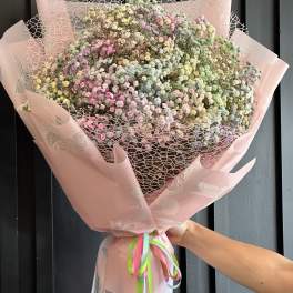 Large pastel bouquet of tiny multicolored flowers wrapped in pink paper
