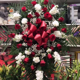 Large standing arrangement of red roses and white carnations with a red bow