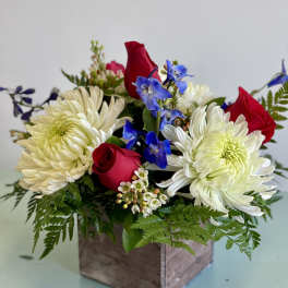 Red roses and white chrysanthemums in a wooden box with blue flowers