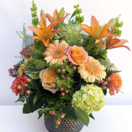 Orange lilies and peach roses in a dark textured vase