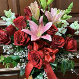 Red roses and pink lilies in a glass vase with a red ribbon