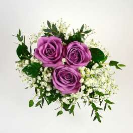 Three purple roses with white filler flowers and greenery
