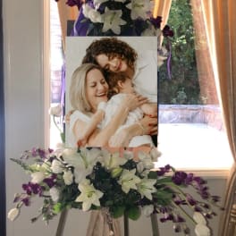 Standing floral easel with white lilies and purple orchids around a photo