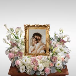 White and pink floral arrangement around a gold picture frame