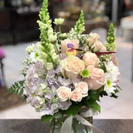 Pastel flower arrangement in a glass vase with roses, hydrangeas, and daisies