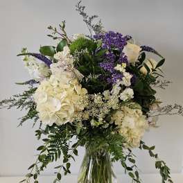 White and purple floral arrangement in a clear glass vase