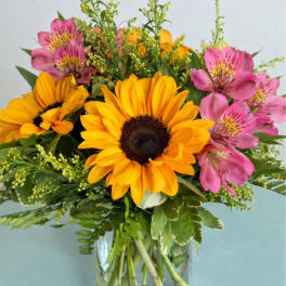 Bouquet of yellow sunflowers and pink alstroemeria in a glass vase
