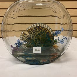Glass fish bowl with a decorative fish and small blue flowers inside
