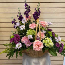 Basket arrangement of pink roses and purple flowers
