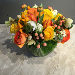 Bright orange and yellow mixed flower arrangement in a glass vase