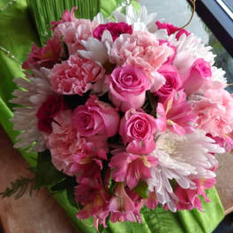 Pink roses and white daisies arranged in a green-wrapped bouquet