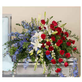 Large casket spray with red roses, white lilies, and blue flowers