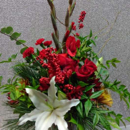 Red roses and white lilies in a glass vase with tall decorative branches