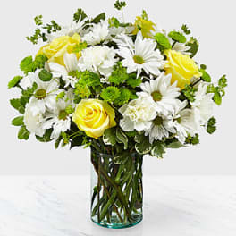 Yellow roses and white daisies in a clear glass vase