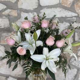 Pink roses and white lilies arranged in a clear glass vase
