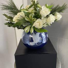 White roses and lilies arranged in a blue glass vase