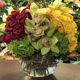Bouquet of red and yellow roses with green orchids in a glass vase