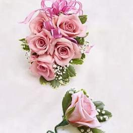 Corsage and boutonniere set with pink roses, white filler flowers, and a pink ribbon bow.