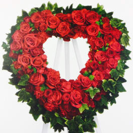 Heart-shaped wreath of red roses on a white easel