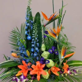 Tropical flower arrangement with orange birds of paradise and blue blooms