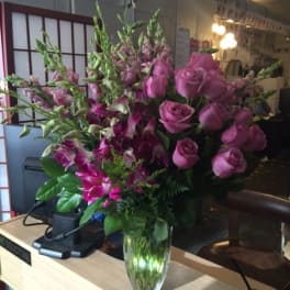 Pink roses and orchids arranged in a clear glass vase