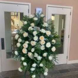 Standing spray of white roses and greenery on an easel