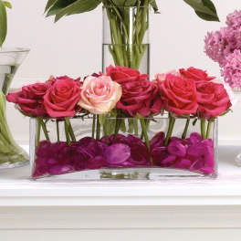 Pink and magenta roses arranged in a clear rectangular vase