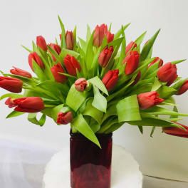 Red tulips arranged in a dark glass vase