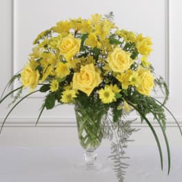 Yellow roses and daisies arranged in a clear glass vase