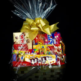 Basket of assorted candy bars wrapped in clear cellophane with a gold bow