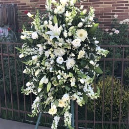 Large white funeral spray on an easel with lilies and daisies