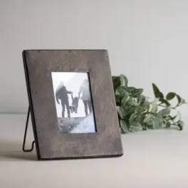 Wooden photo frame with greenery behind it