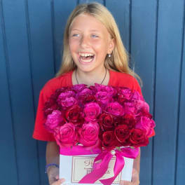 Girl holding a box of pink and red roses with a ribbon