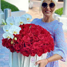 Woman holding a large box of red roses with white orchids