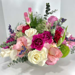Mixed bouquet of pink, white, and magenta roses with tulips in a low vase