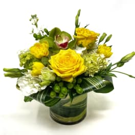 Yellow roses and white blooms arranged in a glass vase