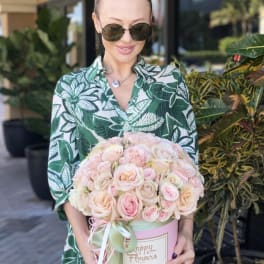 Woman holding a pink box of pale pink roses