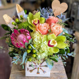 Mixed bouquet with peach roses, green orchids, and a protea in a decorative box