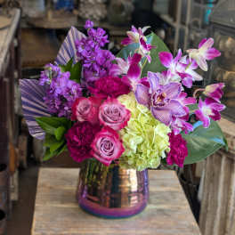 Bouquet of purple orchids, roses, and hydrangea in a metallic vase